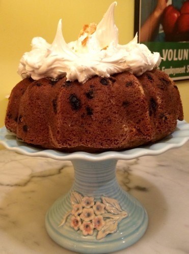 A bundt cake with whipped cream and a paper crown on top.