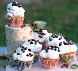 Cupcakes topped with whipped cream and chocolate chips on a wooden stand.