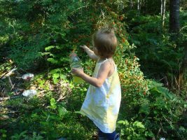 A young girl in a white dress exploring a lush garden.