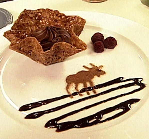A star-shaped chocolate dessert with chocolate drizzle and moose decoration.